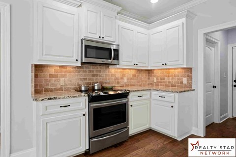 A kitchen with white cabinets and a brick backsplash.