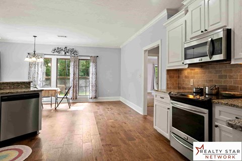 A kitchen with wooden floors and white cabinets.