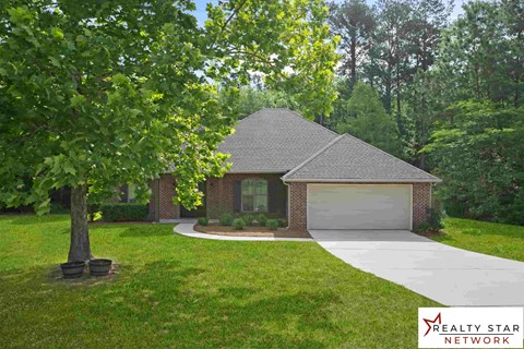 A house with a garage is surrounded by greenery.