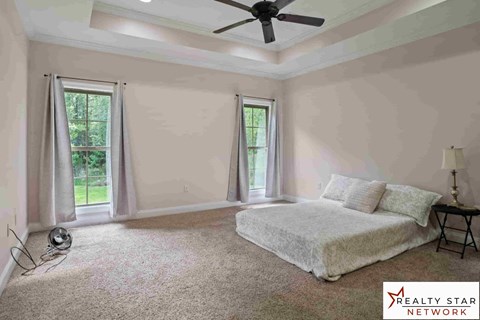 A bedroom with a bed, a ceiling fan, and a window with curtains.
