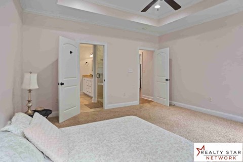 A bedroom with a bed, a lamp, and a ceiling fan.