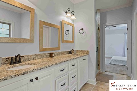 A bathroom with a marble countertop and two framed mirrors above it.