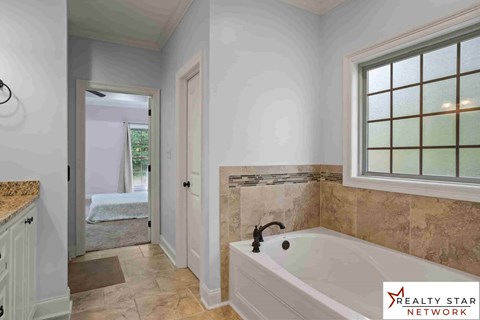 A bathroom with a tub, sink, and a window.