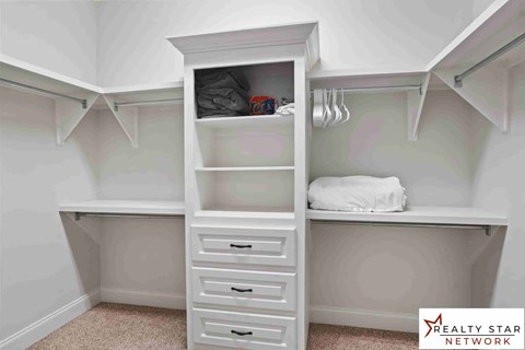 A white cabinet with drawers is in a room with white walls.