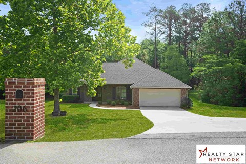 A house with a driveway and a brick pillar with the number 206 on it.