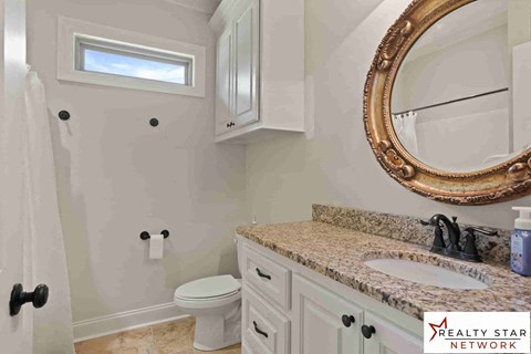 A bathroom with a toilet, sink, and a mirror.