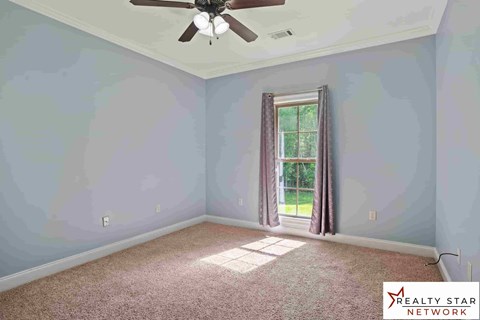 A room with a ceiling fan and a window with curtains.