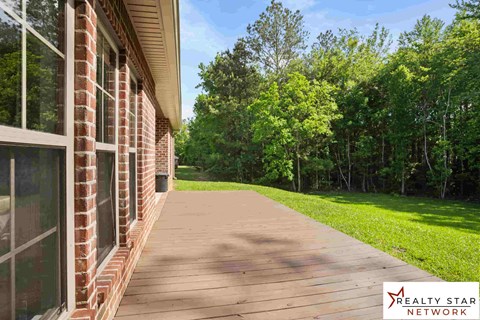 A wooden walkway leads from a brick building to a grassy area.