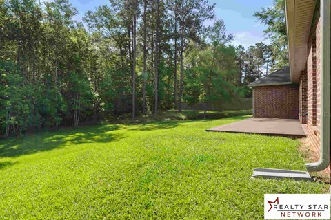 A lush green lawn with a Realty Star Network sign in the foreground.