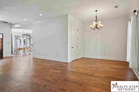 A large empty room with wooden floors and a chandelier.