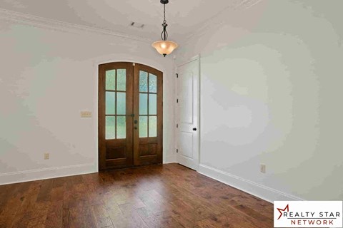 A room with a wooden floor and a chandelier hanging from the ceiling.