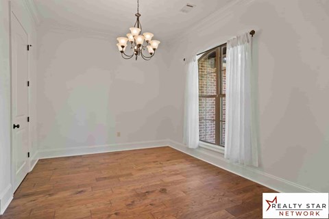 A room with wooden floors and a chandelier hanging from the ceiling.