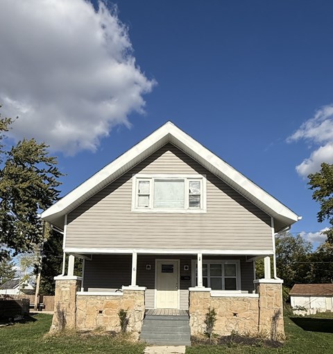 A house with a grey siding and a white door is shown.