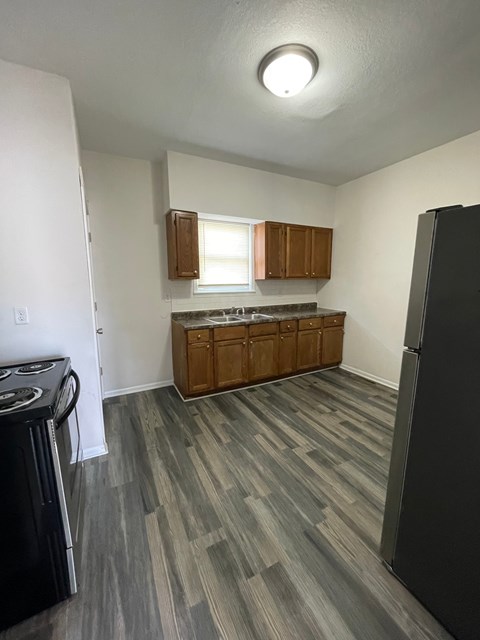 A kitchen with a black refrigerator and wooden cabinets.