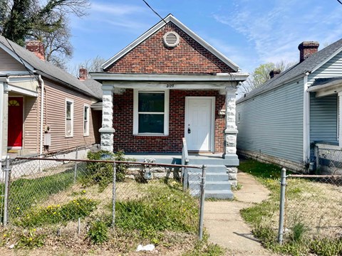 A red brick house with a white door and a small porch.
