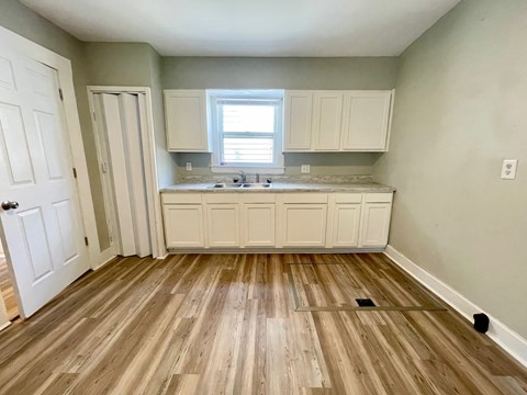 A kitchen with wooden floors and white cabinets.