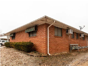 A red brick house with a white pipe on the side.
