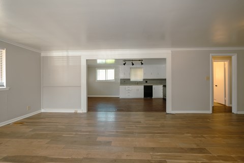A kitchen with white cabinets and a wooden floor.