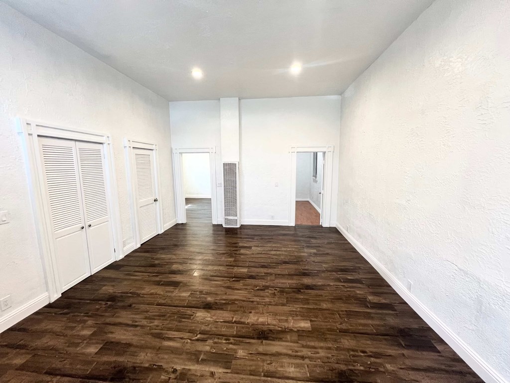 A long hallway with white walls and wooden floors.