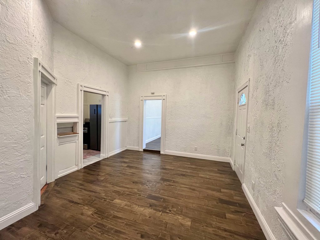A room with wooden flooring and white walls.