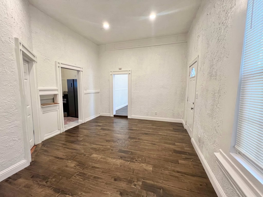 A room with wooden flooring and white walls.