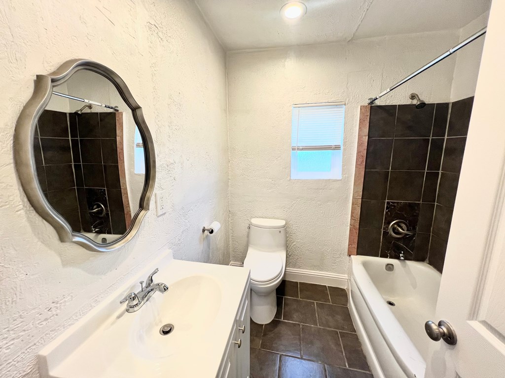 A bathroom with a white sink, toilet, and bathtub.