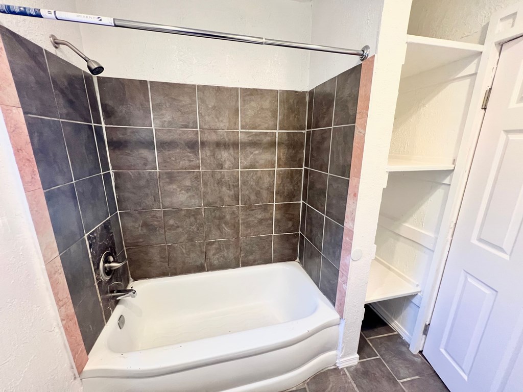 A white bathtub with a shower head and a white door.