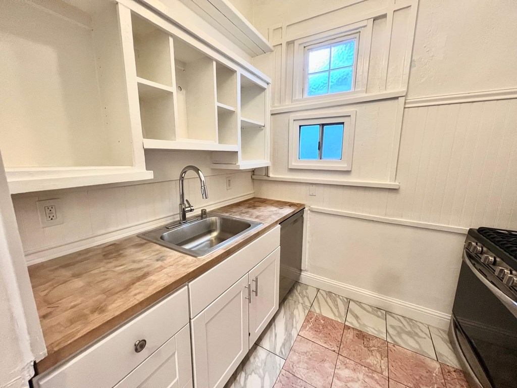 A kitchen with a sink, stove, and cabinets.