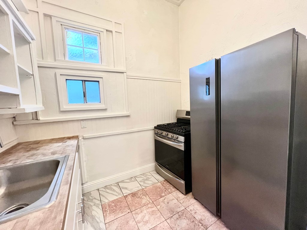 A kitchen with a sink, a window, and a refrigerator.