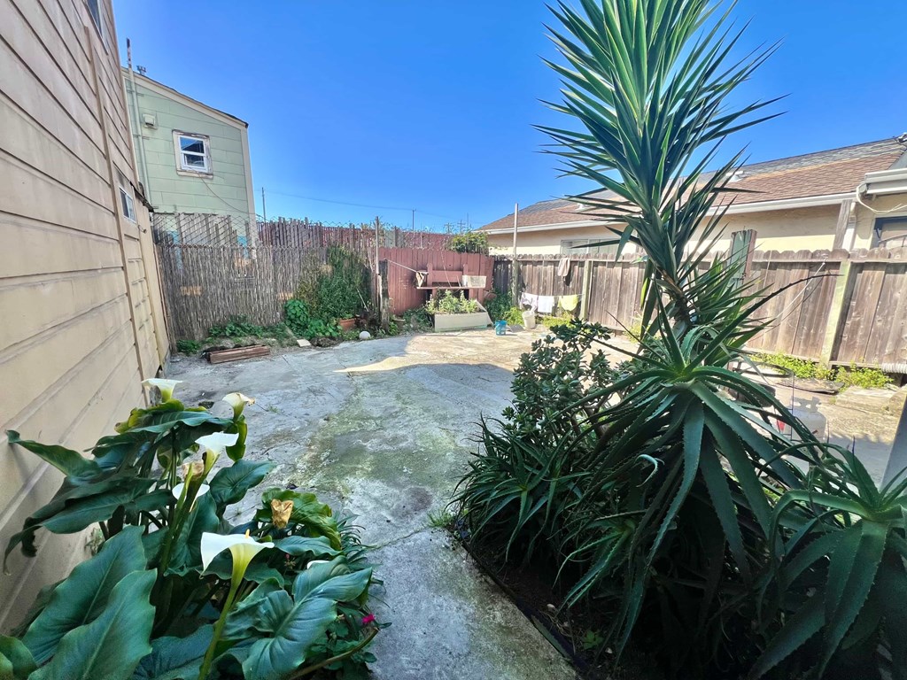 A backyard with a concrete patio and a fence.