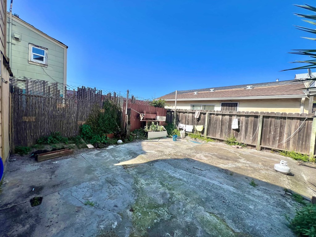 A backyard with a concrete patio and a wooden fence.