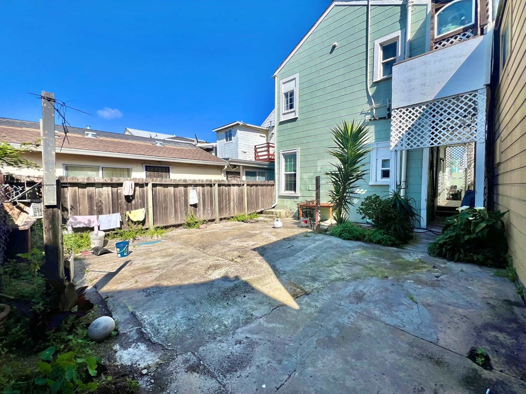 A backyard with a large rock and a wooden fence.