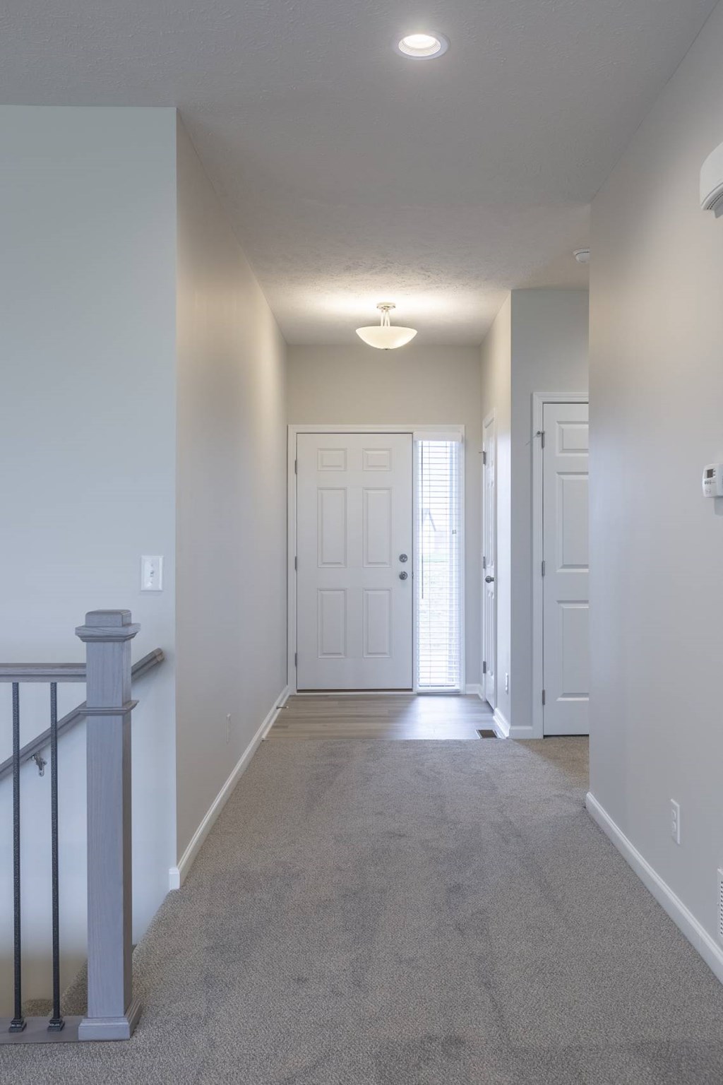 A hallway with a carpeted floor and a light on the ceiling.