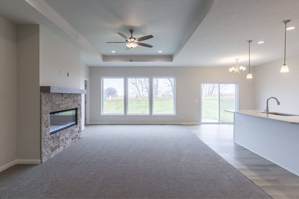 A spacious living room with a fireplace and a ceiling fan.