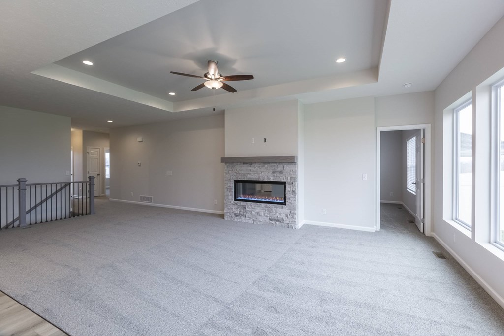 A spacious living room with a fireplace and a ceiling fan.