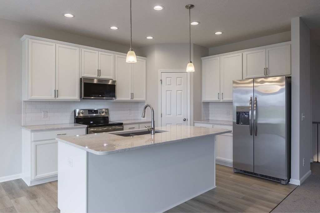 A kitchen with white cabinets and a wooden island.