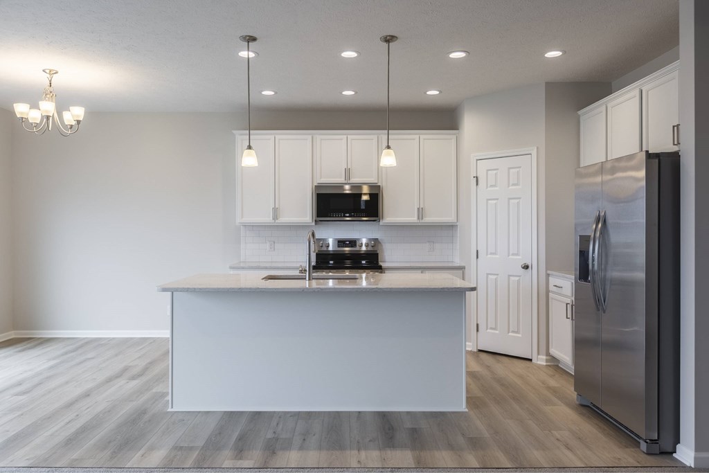 A modern kitchen with a stainless steel refrigerator and a white island.
