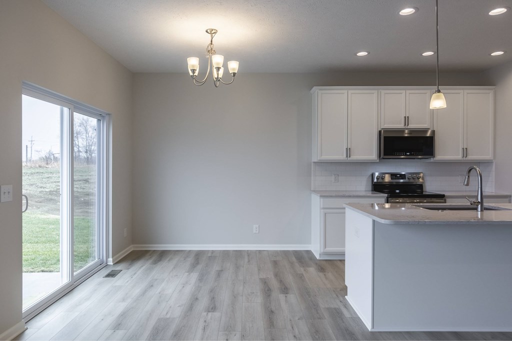 A kitchen with white cabinets and a wooden floor.