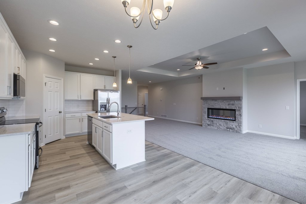 A modern kitchen with a white island and a fireplace.