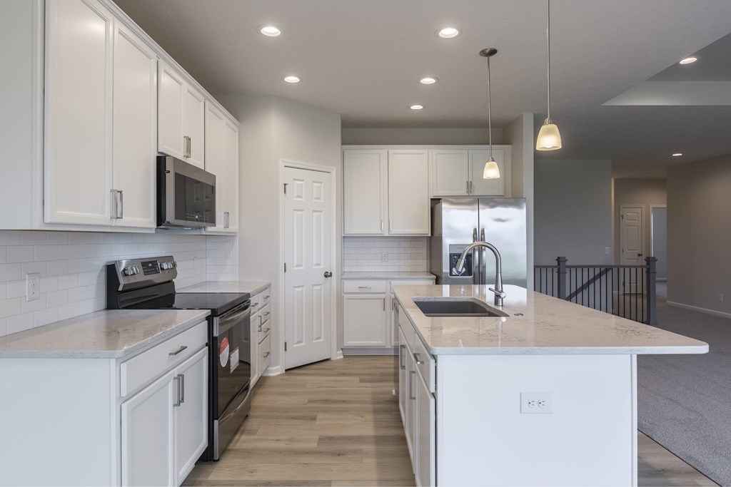 A kitchen with white cabinets and appliances.