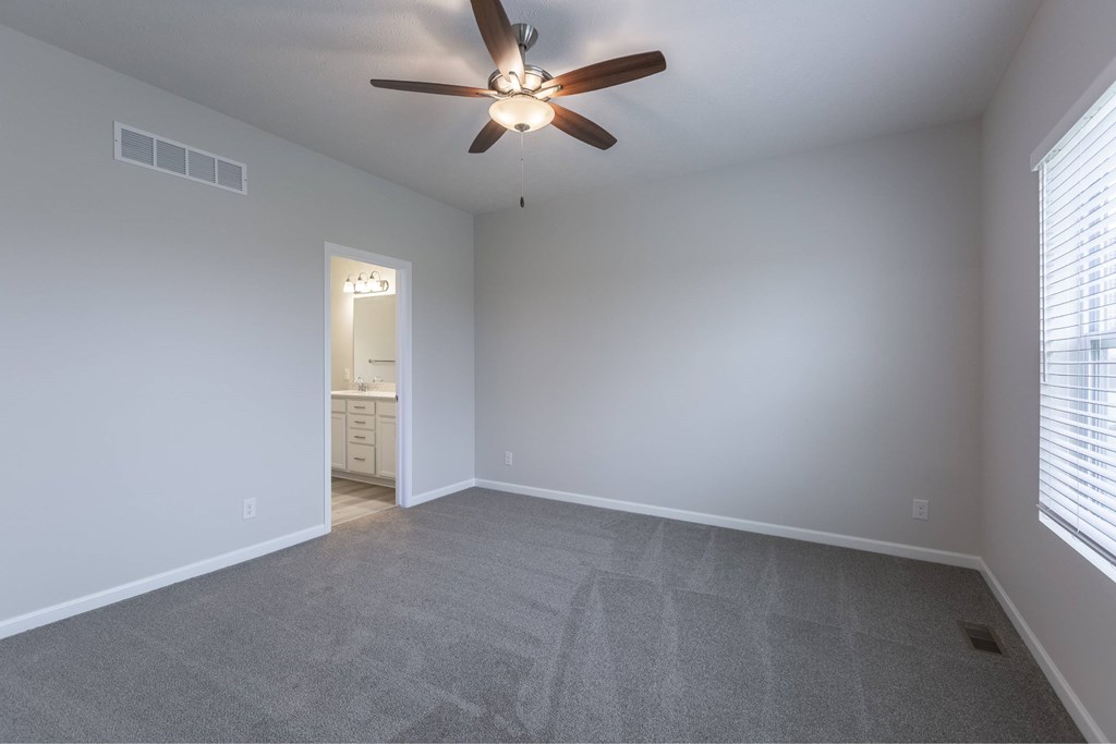 A room with a ceiling fan and carpeted floor.