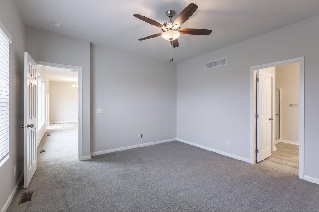 A room with a ceiling fan and carpeted floor.