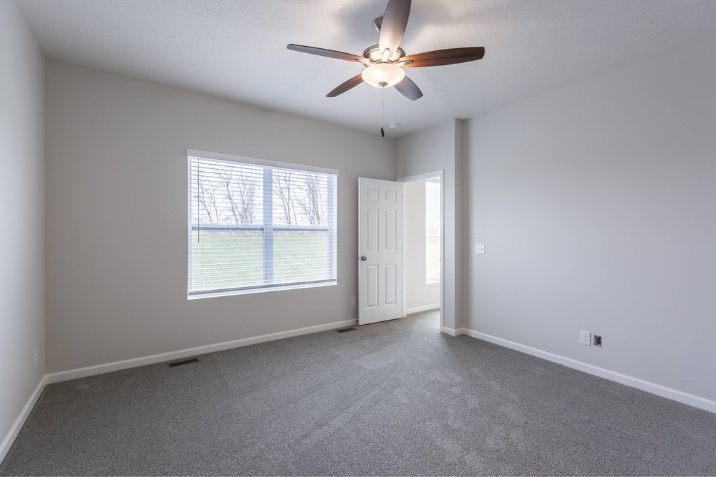 A room with a ceiling fan and a window with blinds.