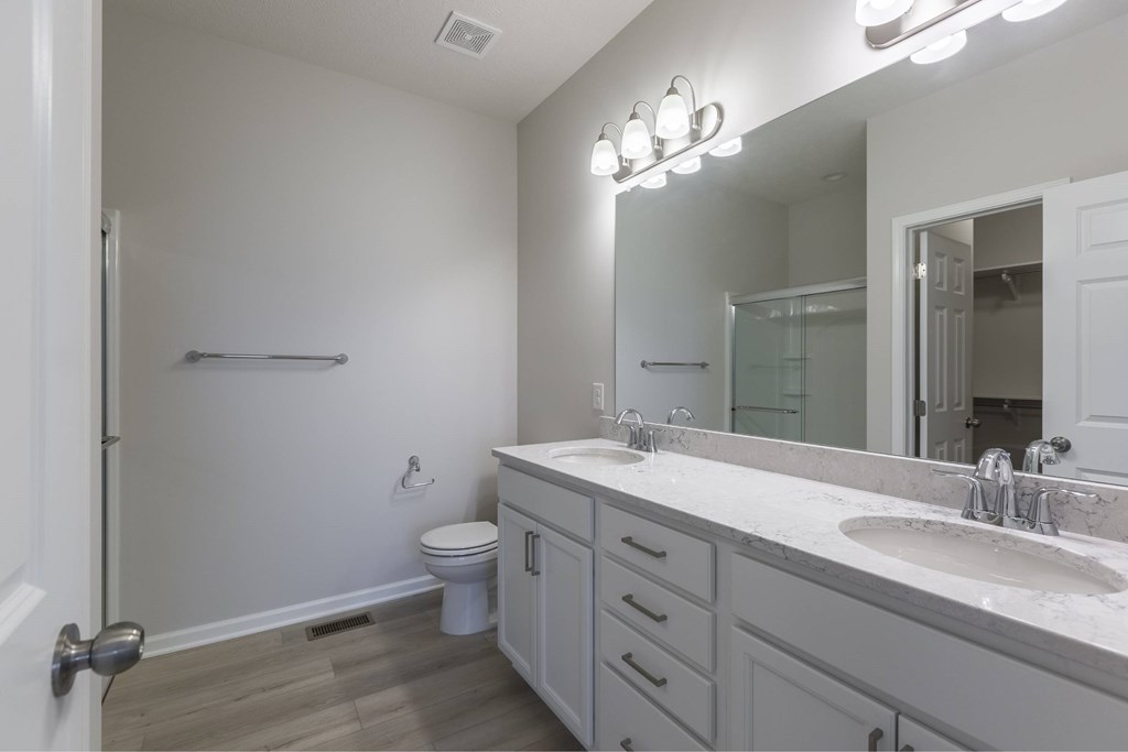 A bathroom with a toilet, sink, and mirror.