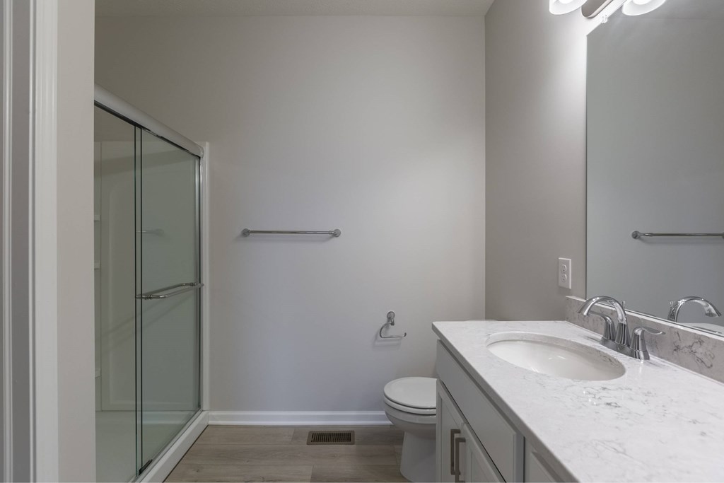 A bathroom with a toilet, sink, and shower.