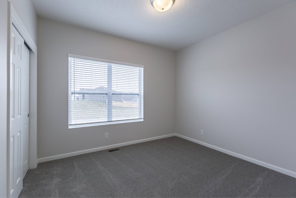 A room with a window and a carpeted floor.