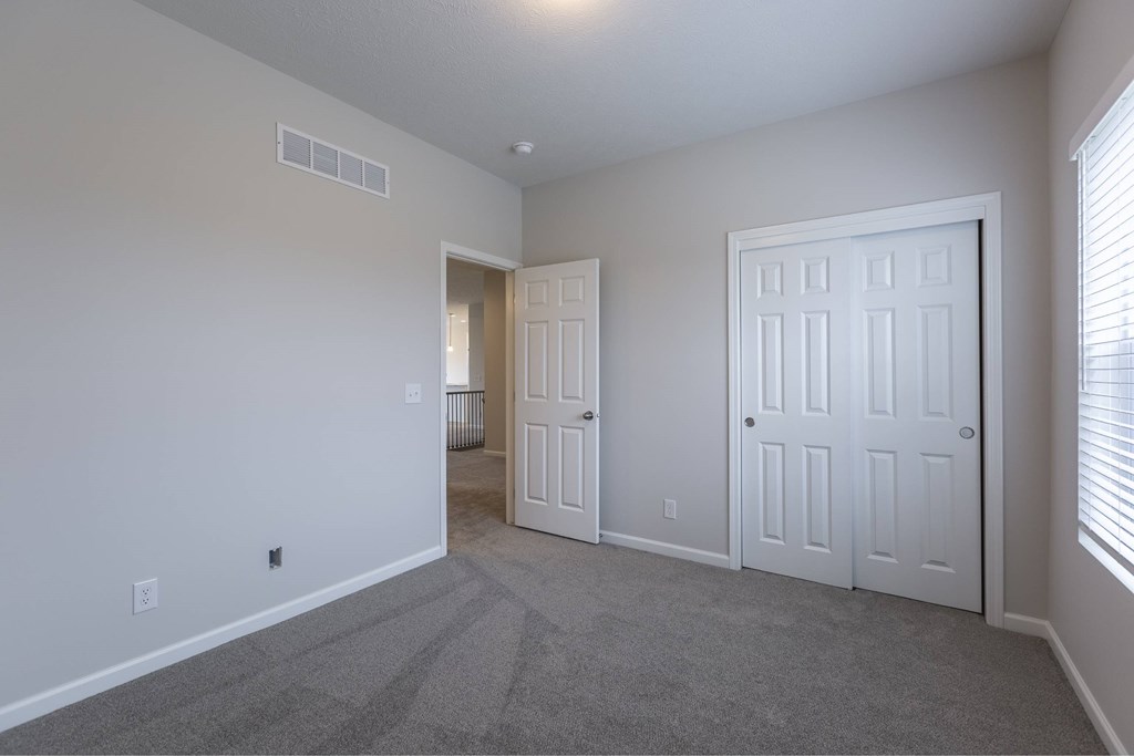 A room with a carpeted floor and two white doors.