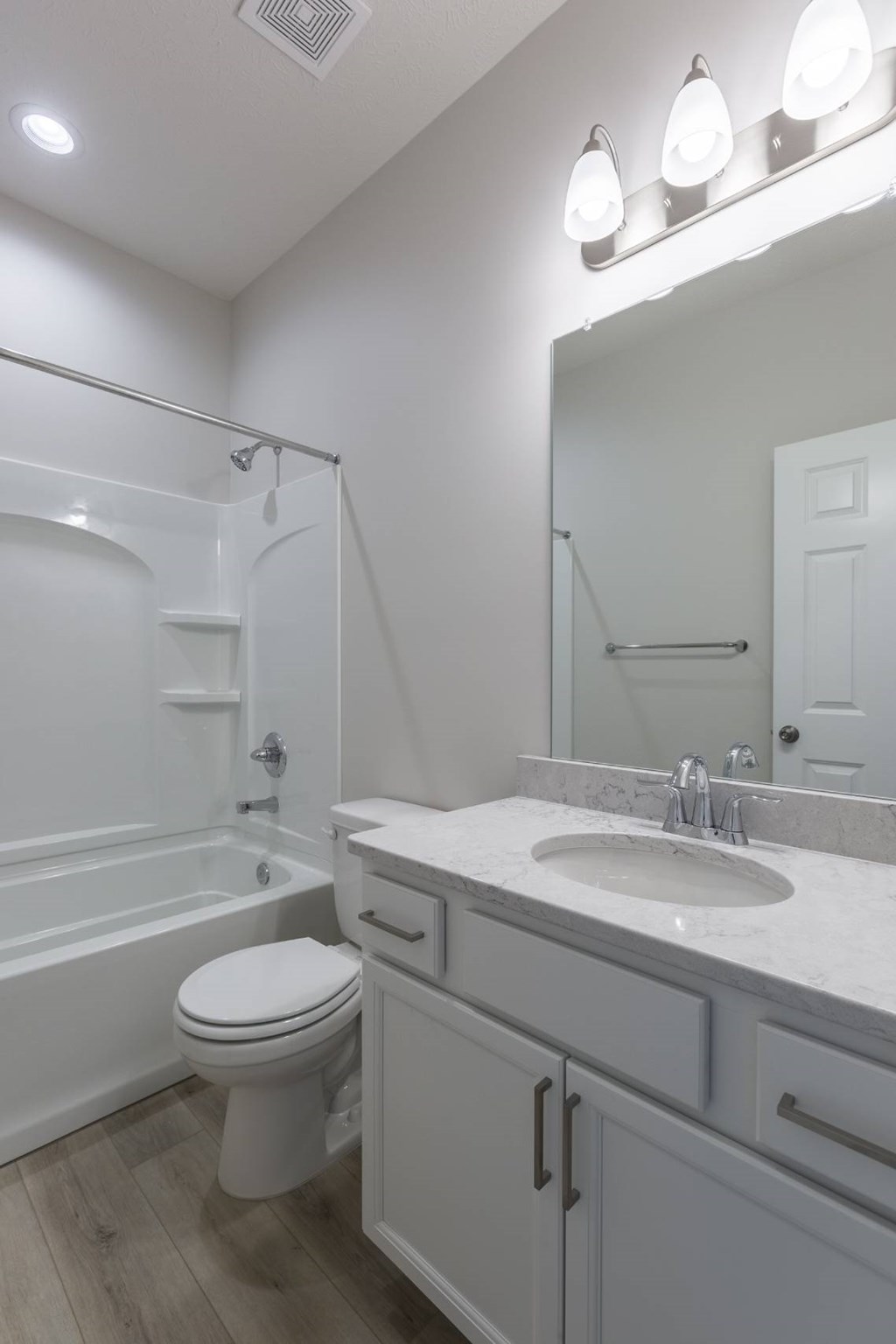 A white bathroom with a toilet, sink, and mirror.