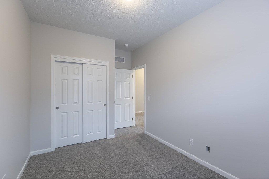 A room with a white door and carpeted floor.