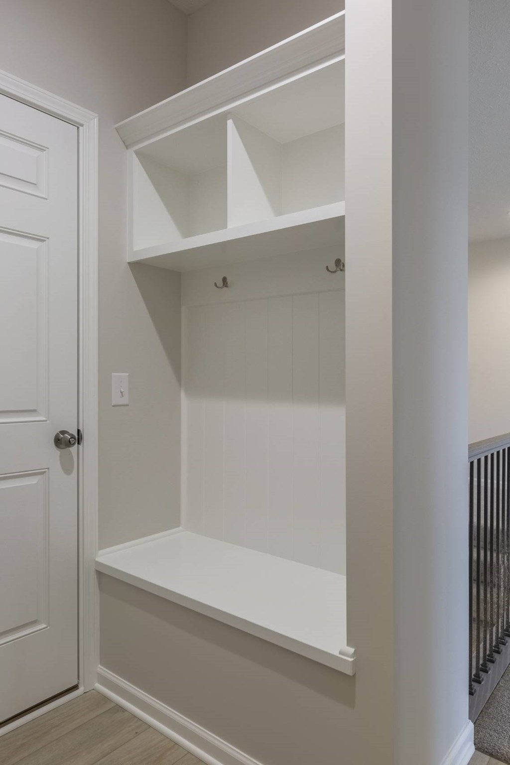 A white door is on the left of a white shelving unit.